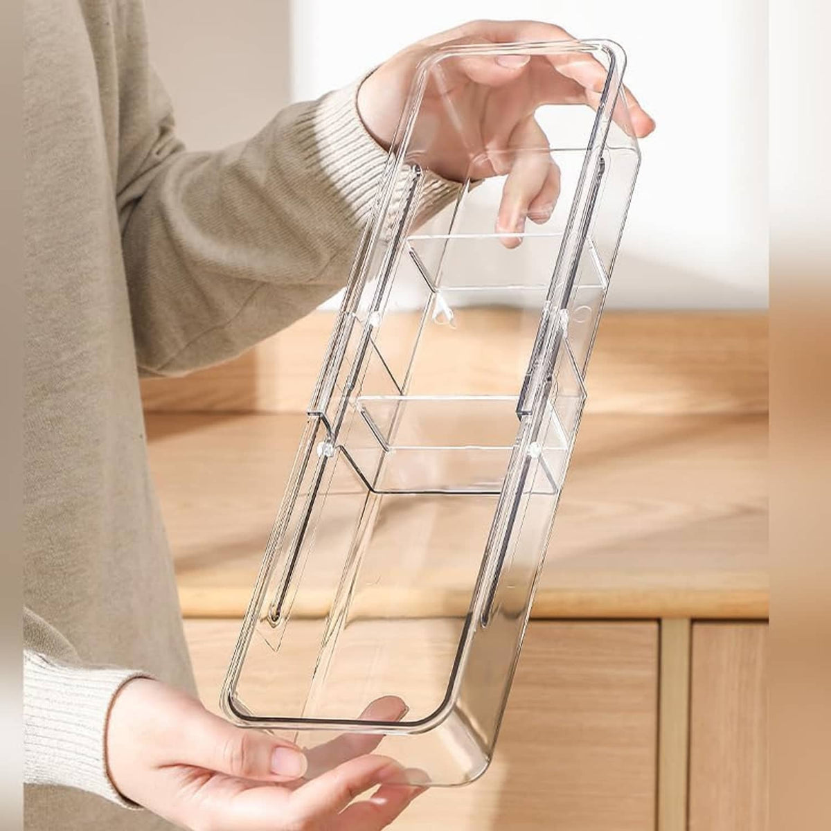 Hand holding a clear acrylic tea bag holder with open divider structure