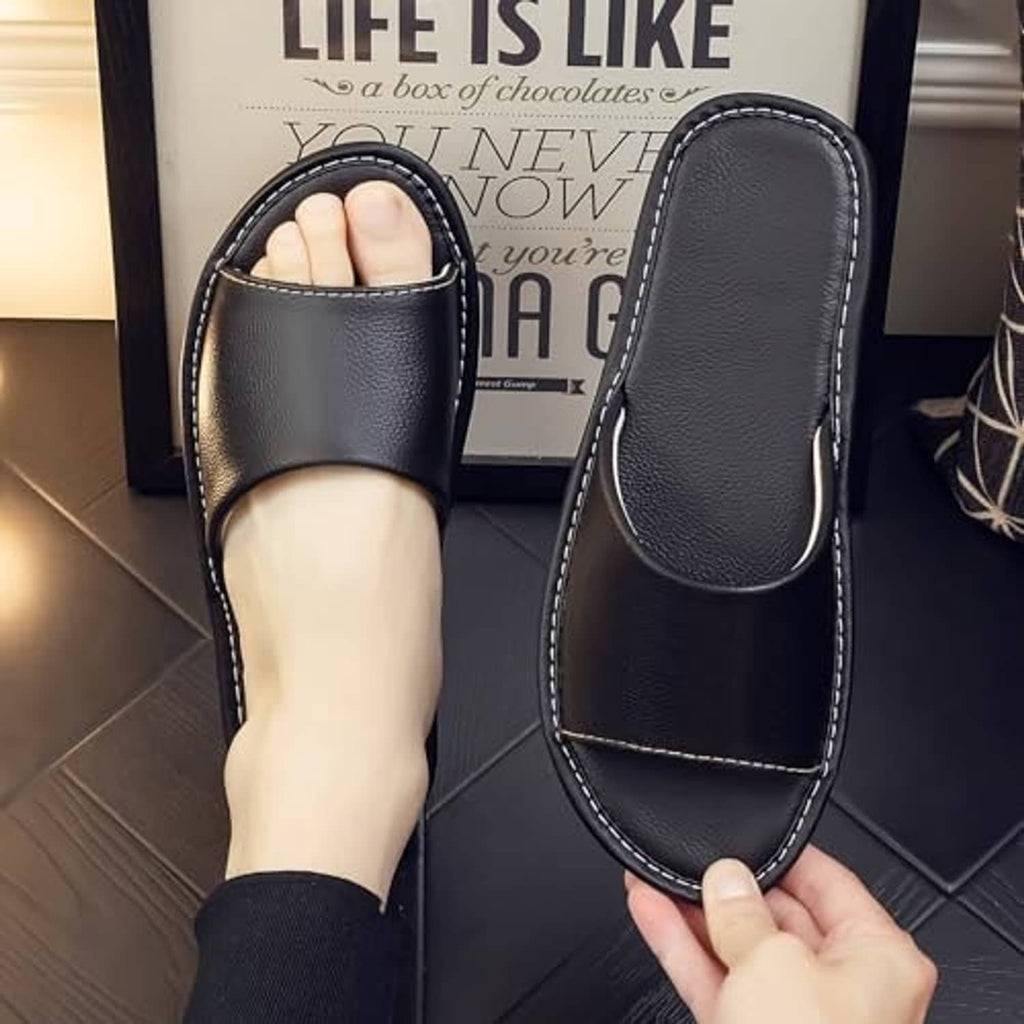 Black leather slide sandal with wide strap and open toe, worn view.