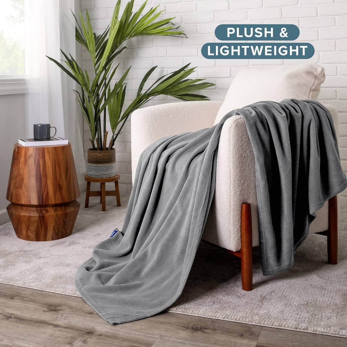 Gray lightweight throw blanket draped over a chair, plush fleece surface