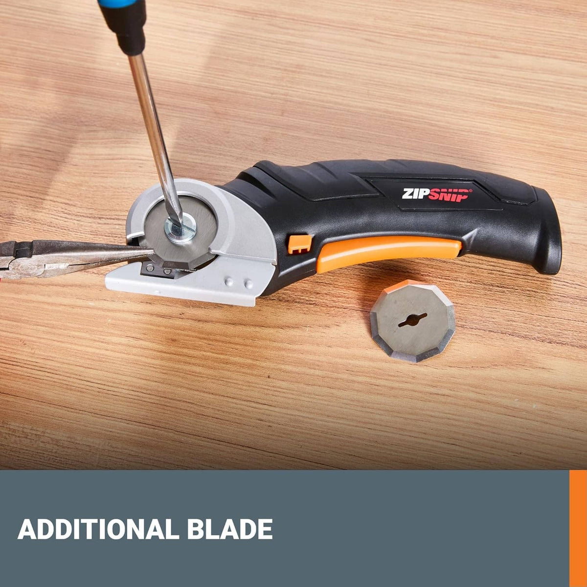 Black and orange electric scissors cutting wood with an extra blade included