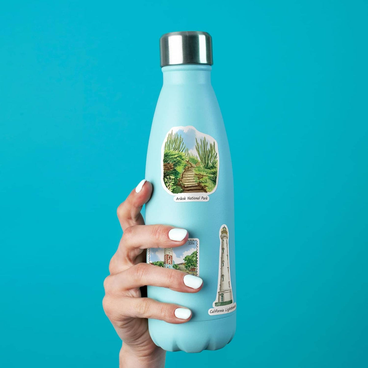 Hand holding a blue bottle with Aruba landscape and lighthouse stickers