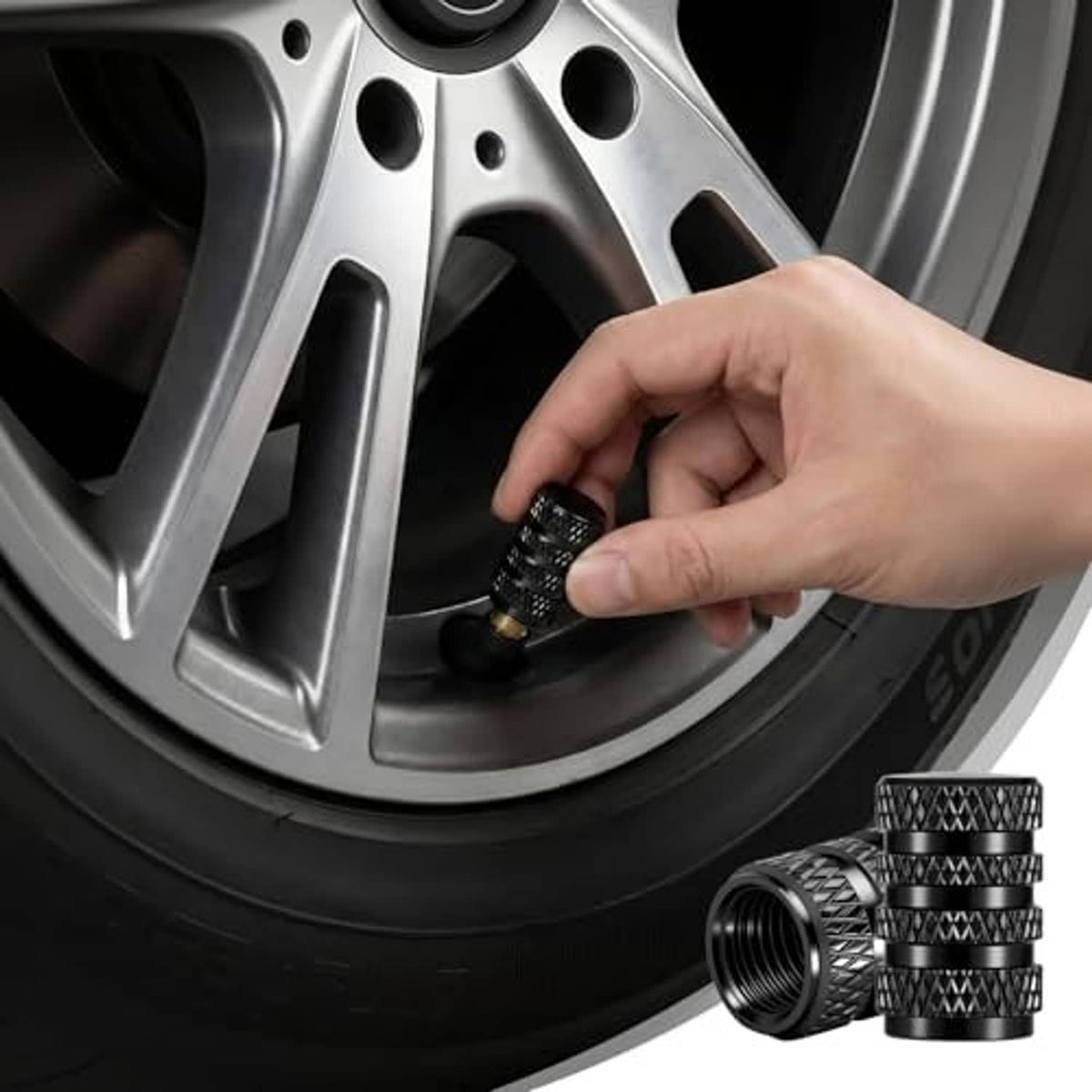 Hand installing black knurled tire valve stem cap on wheel valve stem