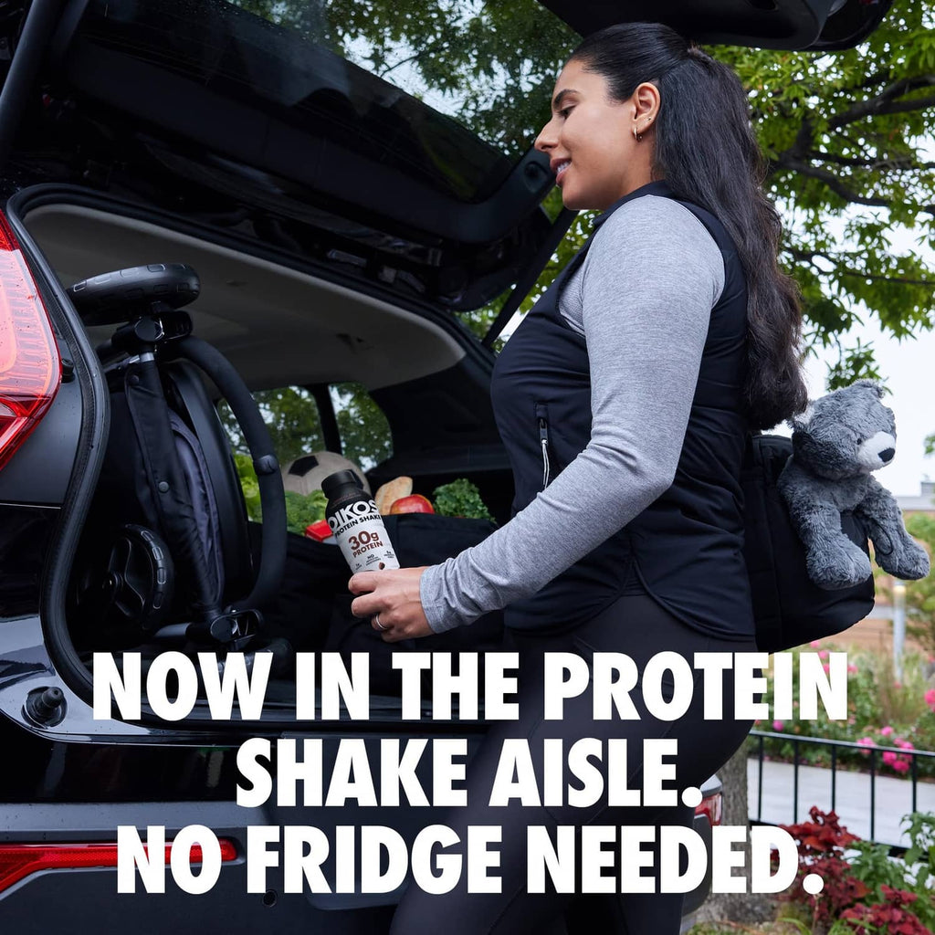 Oikos protein shake bottle in a bag with a woman near an open car trunk