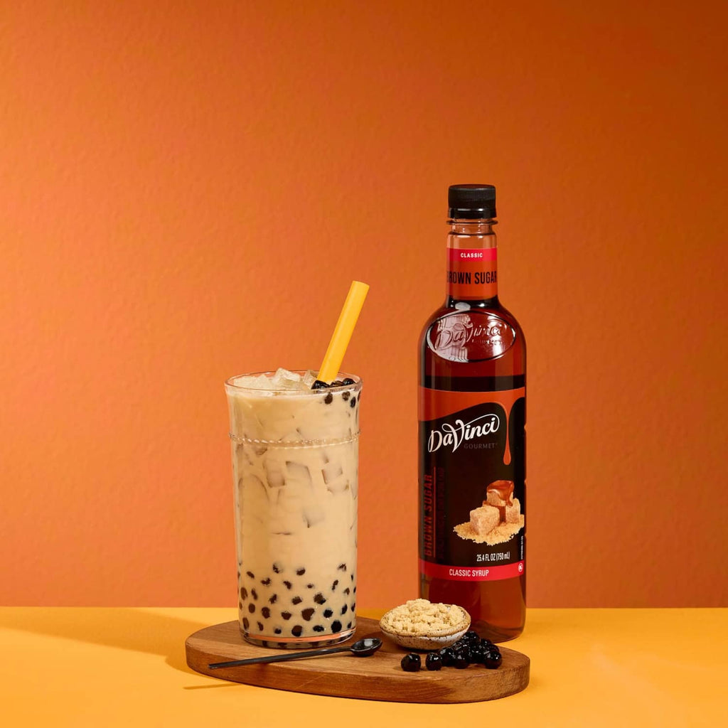 Brown sugar syrup bottle with iced drink, tapioca pearls, and brown sugar pieces