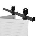 Black sliding barn door track hardware with roller hangers mounted on a bar