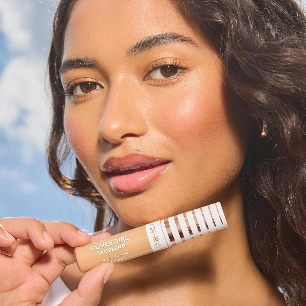 Concealer tube held near face, matte full-coverage look on natural complexion