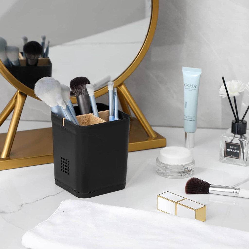 Black toothbrush holder with brushes on a countertop next to bathroom essentials
