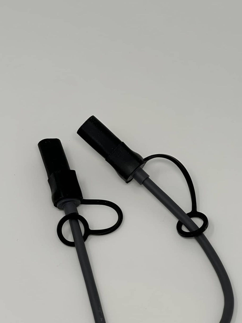 Set of black silicone cable end caps with lanyard loops for secure sealing