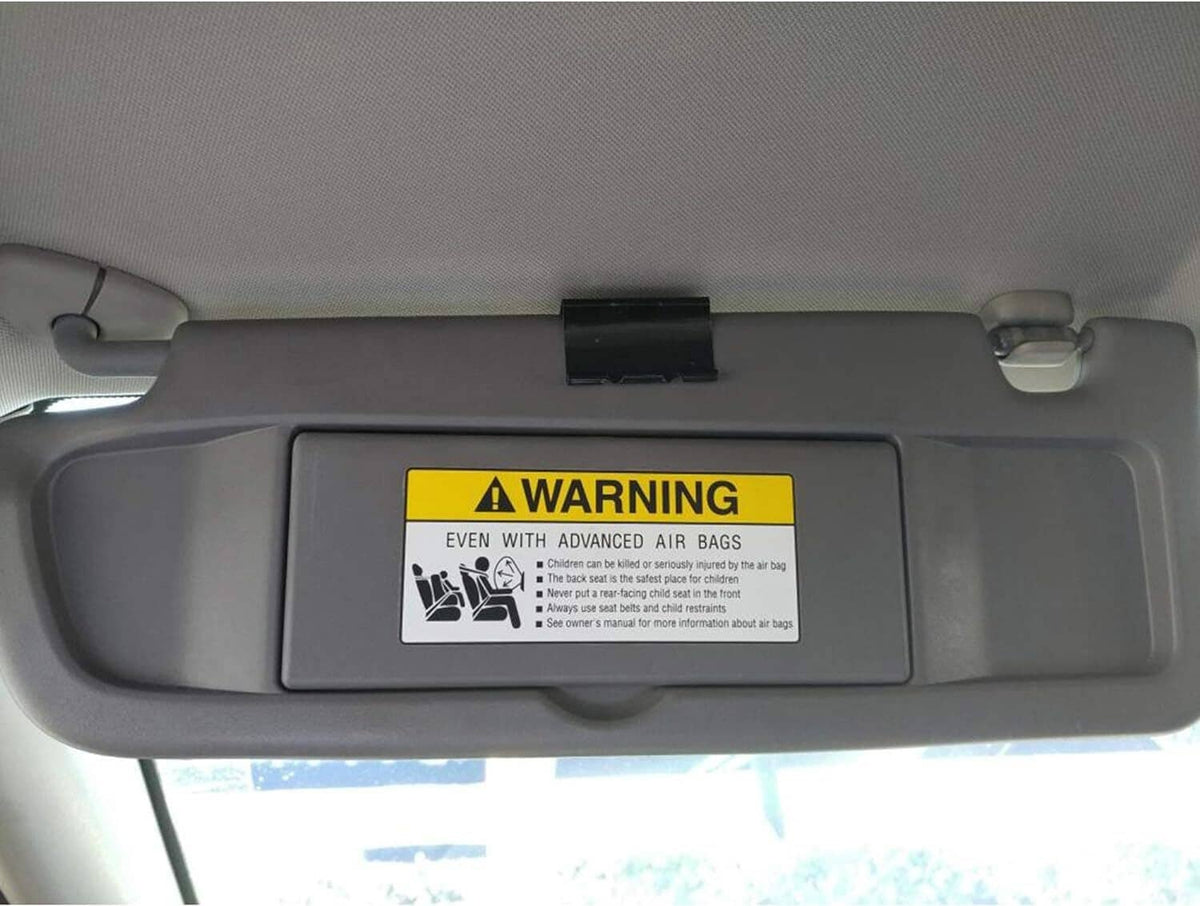 Dark gray car sun visor pair with AIR BAG WARNING label and center latch