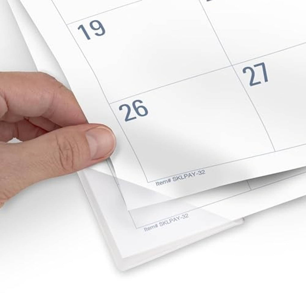 Hand lifting a printed month page corner from the desk calendar planning pad