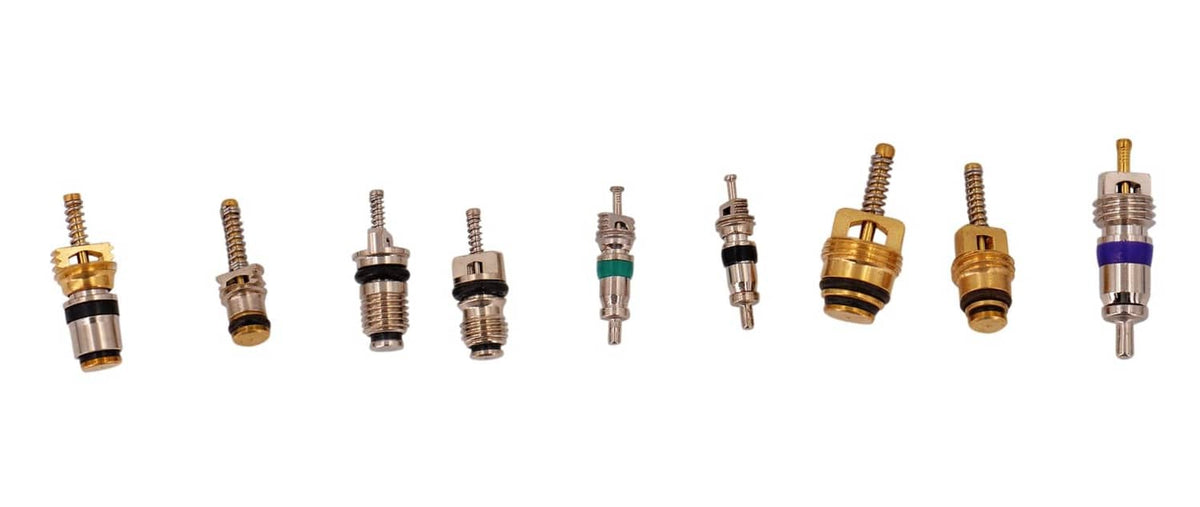Assorted valve cores and small fittings with brass, purple, and silver parts.