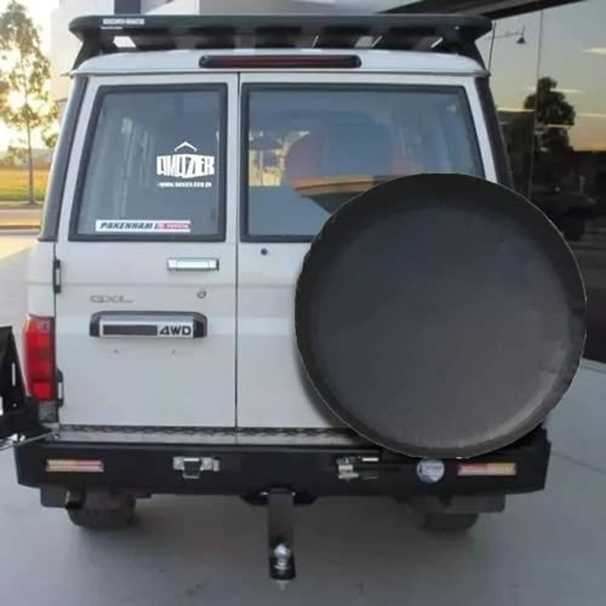 Universal spare tire cover installed on SUV rear, round dark gray/black cover