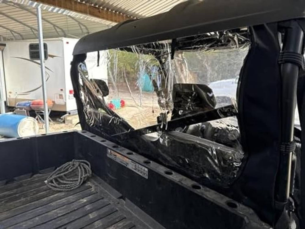 Soft rear windshield with clear window and black frame installed in a workshop