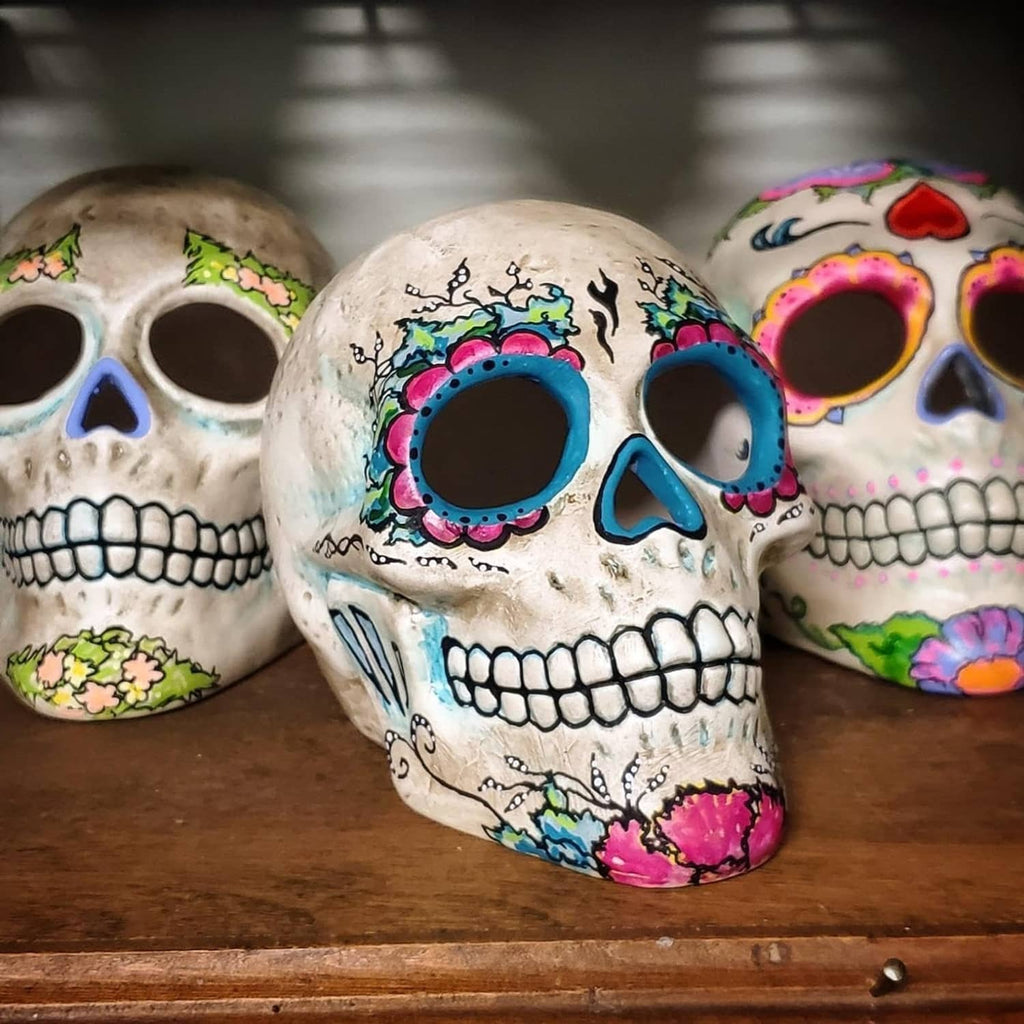 Painted decorative skull set on wooden surface with colorful designs and dark eyes