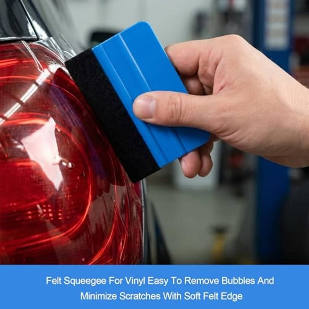 Hand holding a blue felt squeegee to smooth vinyl on a car