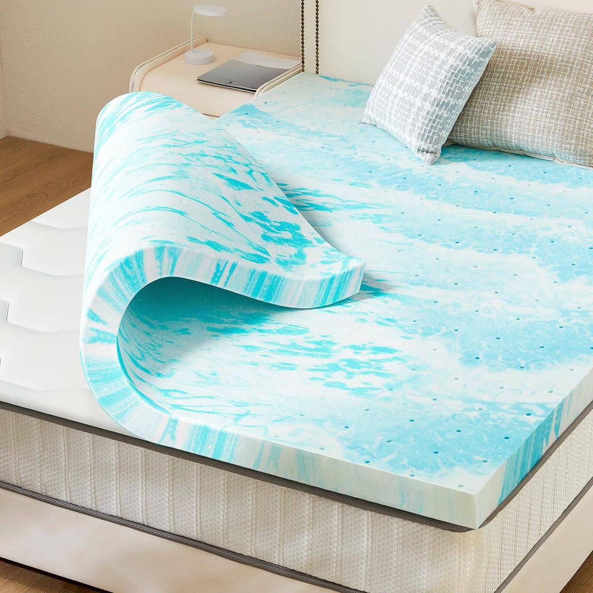 Blue memory foam mattress topper laid flat on a bed with a rolled section