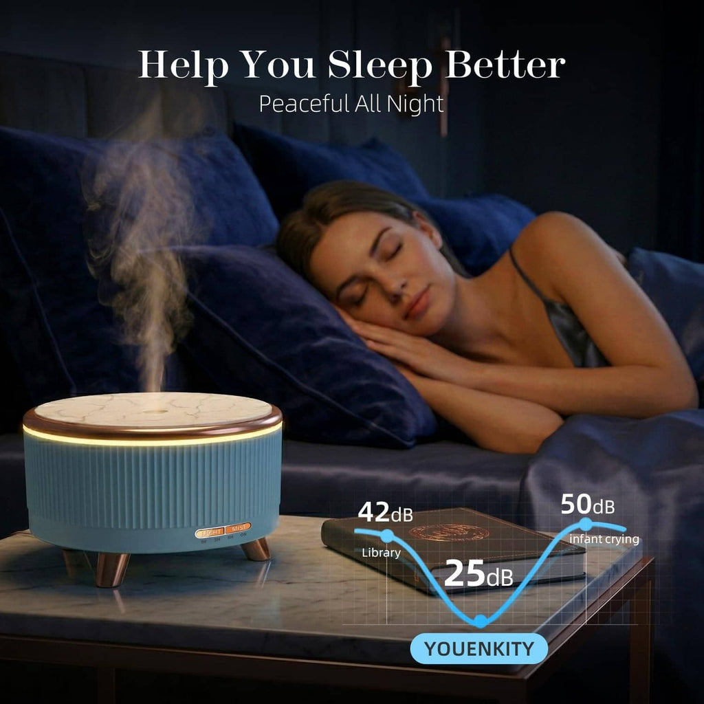 Blue ultrasonic essential oil diffuser on bedside table with soft mist in a dark room.