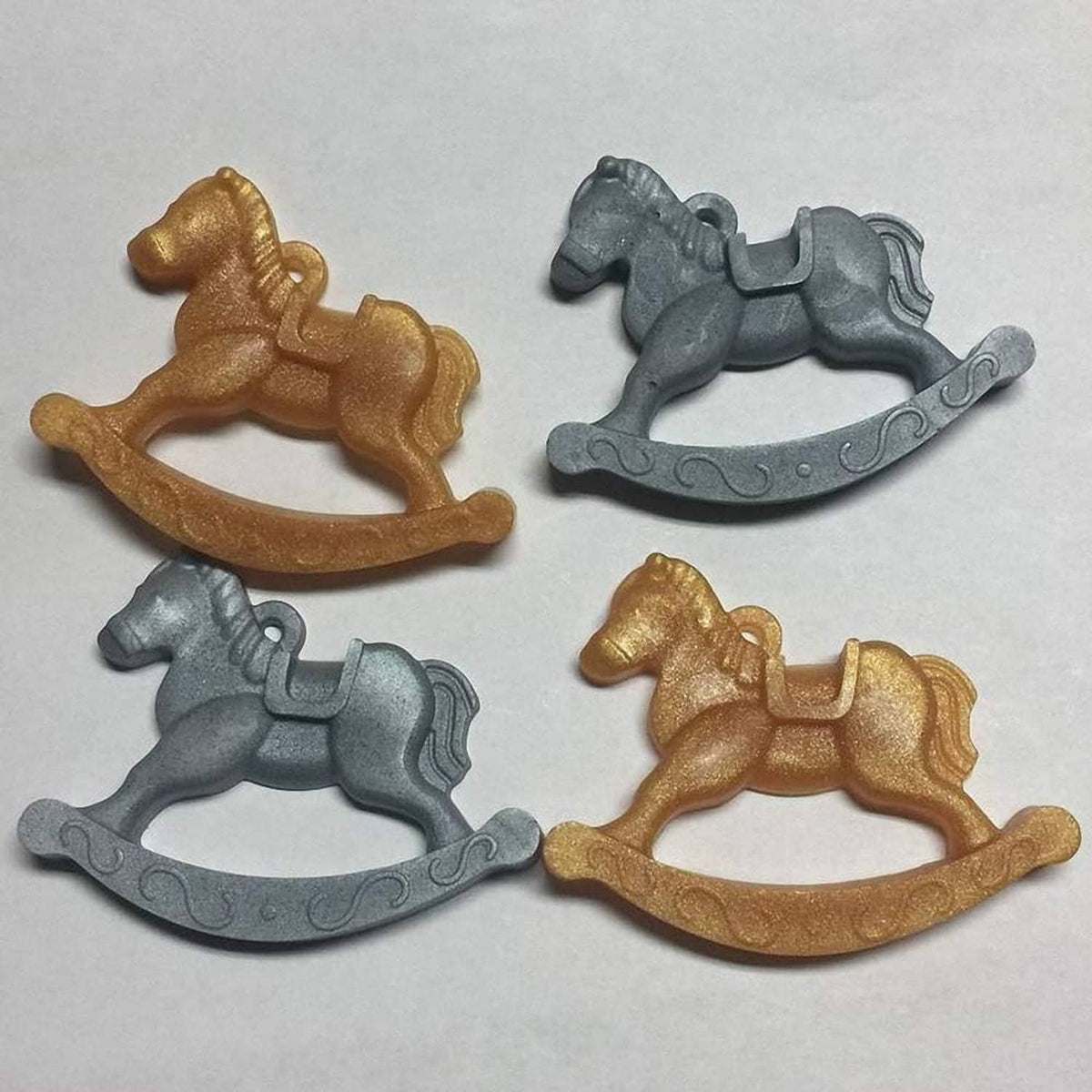 Set of four rocking horse candies in gold and gray colors.