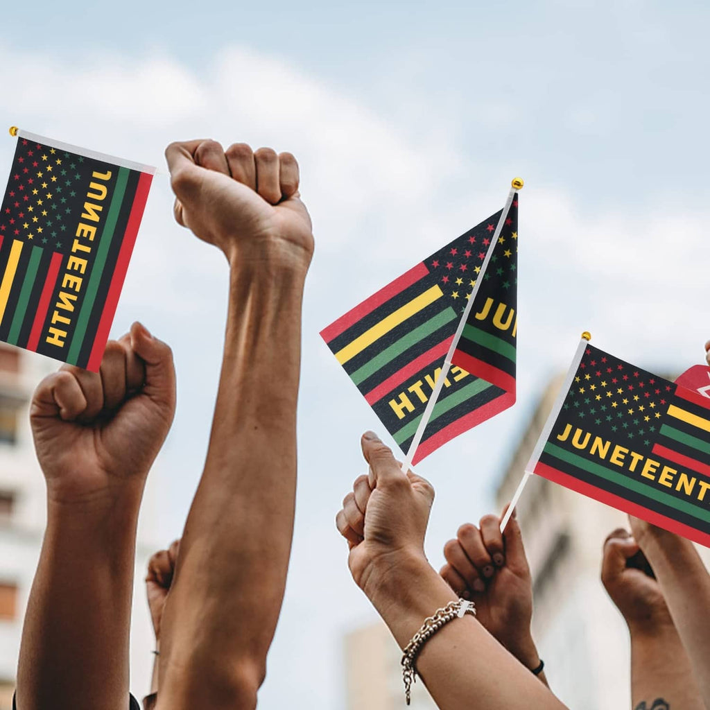 People holding Juneteenth mini flags with gold-tipped poles and “JUNETEENTH” text