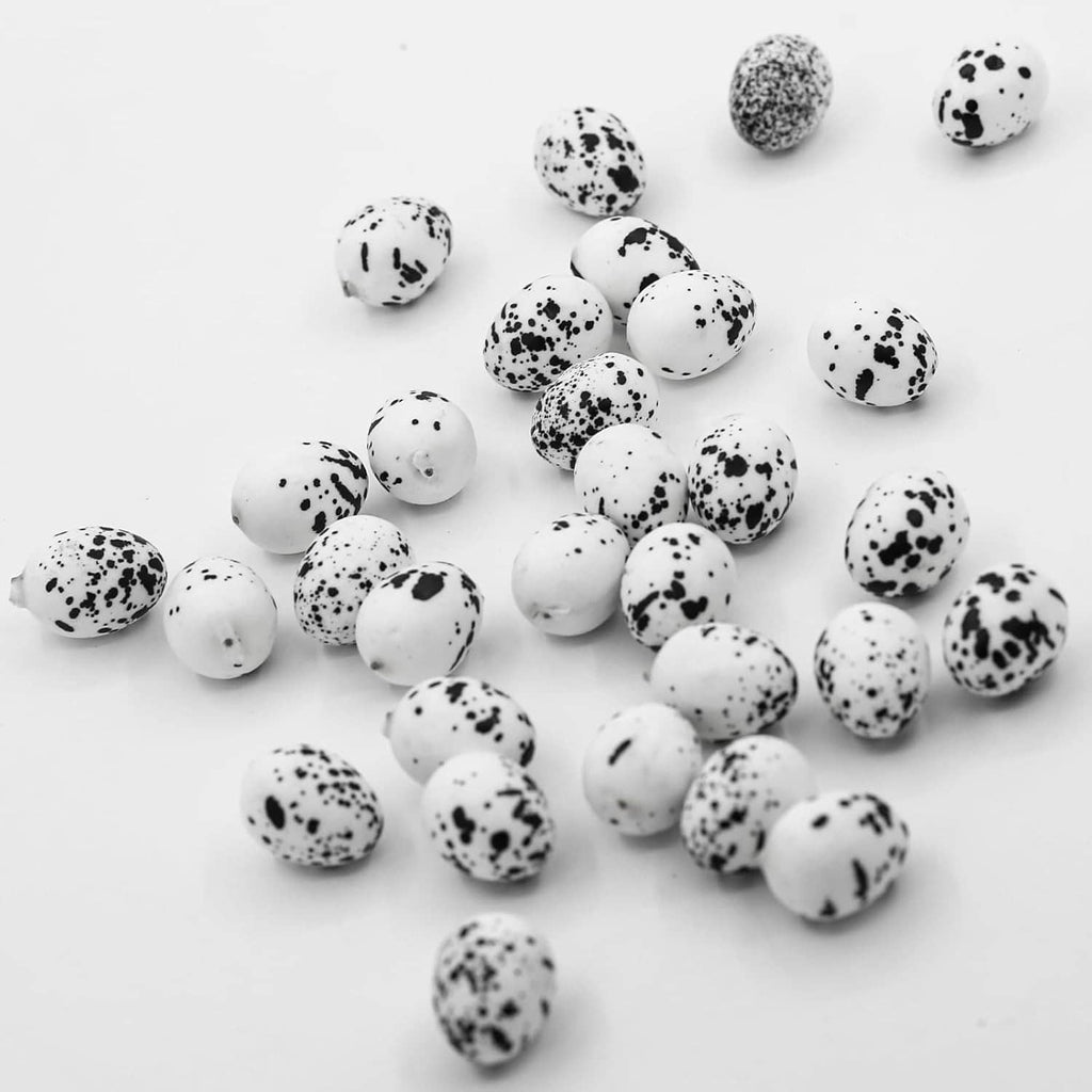 Artificial quail eggs spread out, white shells with black speckles for decoration