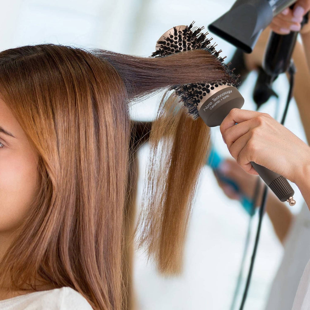 Round hair brush used while blow-drying; hand holds the brush near hair roots