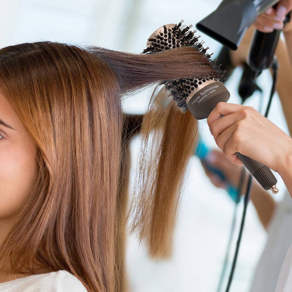 Round hair brush used while blow-drying; hand holds the brush near hair roots