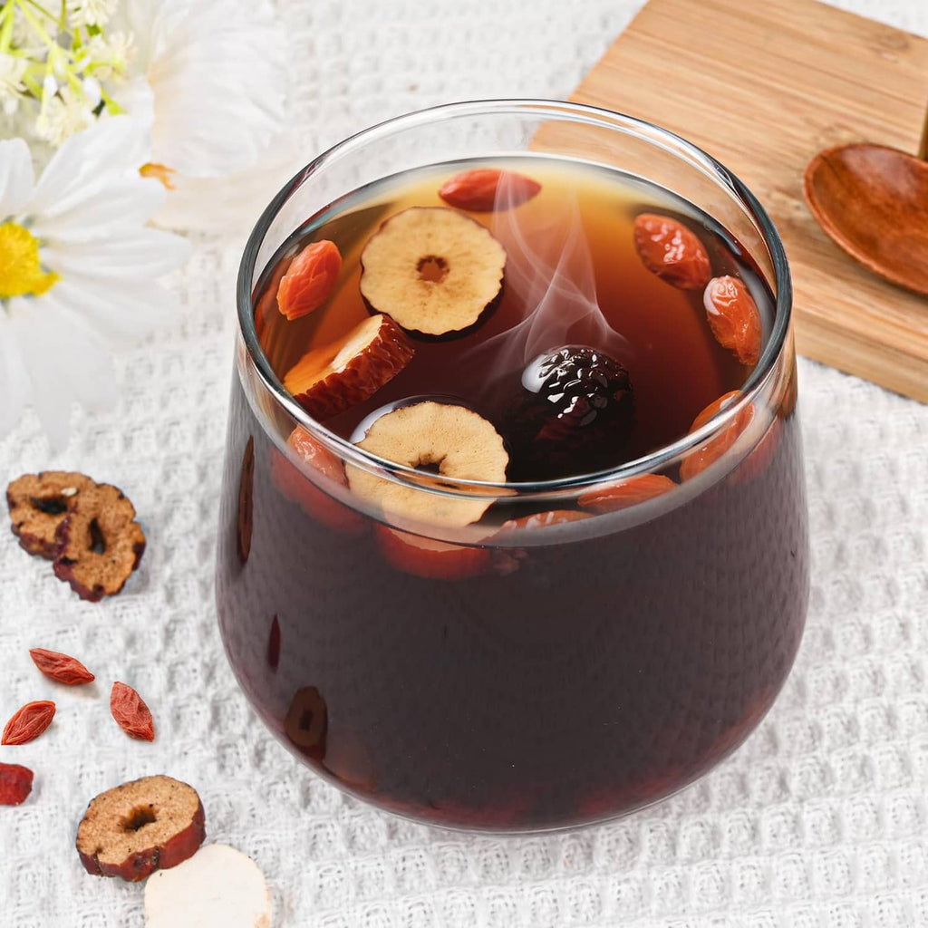 Glass cup of dark herbal tea with dried root slices floating inside