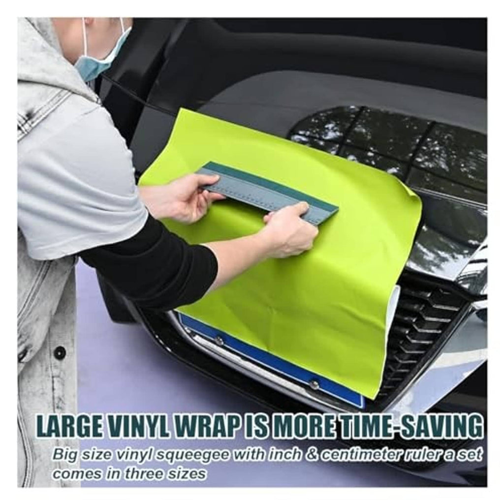 Person applying vinyl wrap using a gray squeegee with ruler on a car window