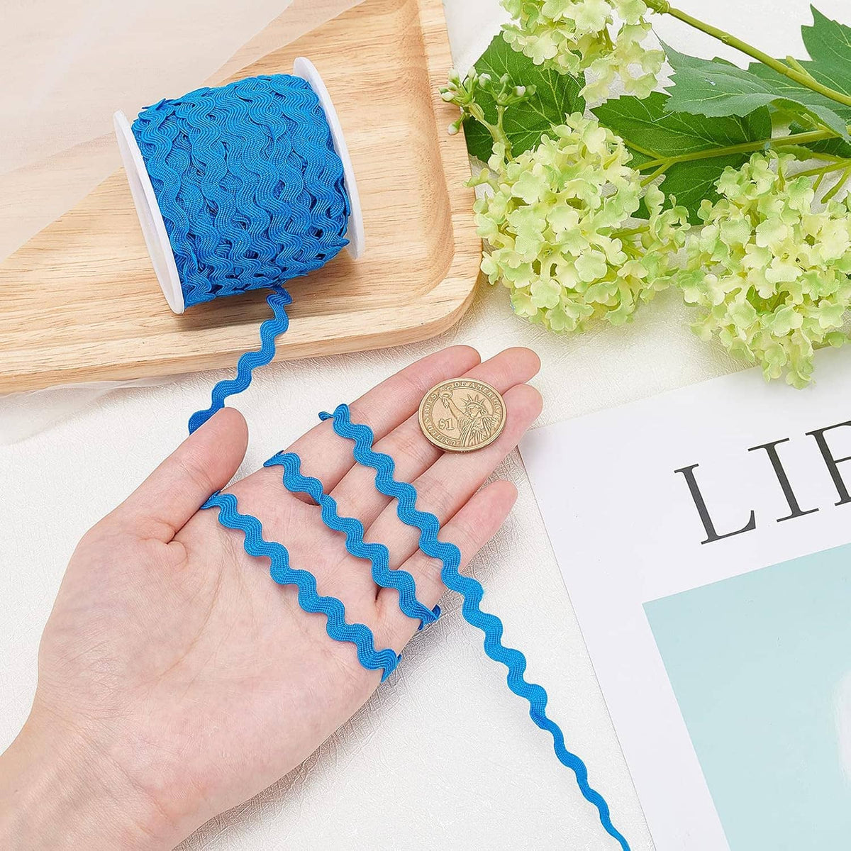 Blue wave sewing ribbon trim held in hand, ruffled wavy edge fringe with spool.