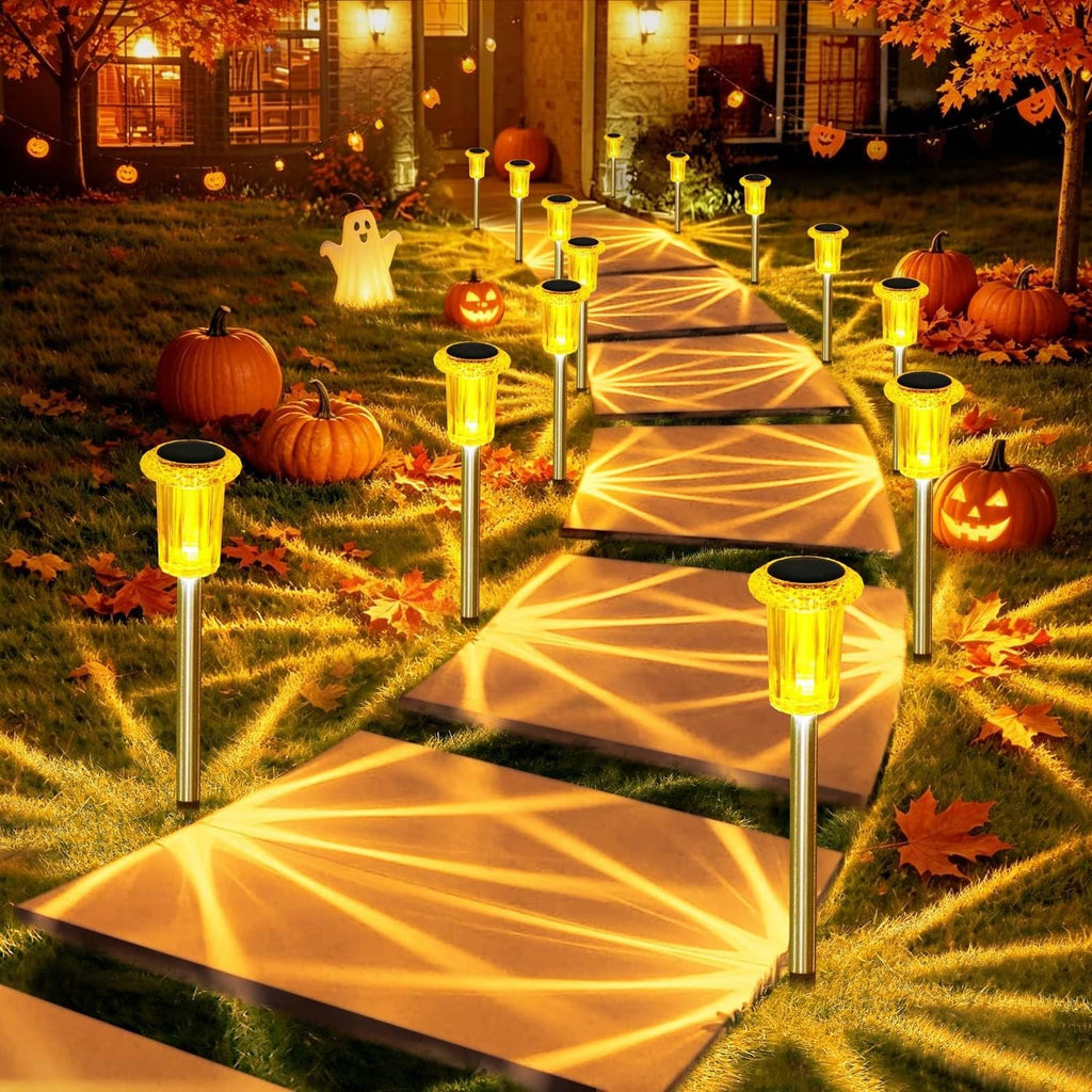 Set of amber solar spike lights with lantern heads, casting starburst glow on walkway