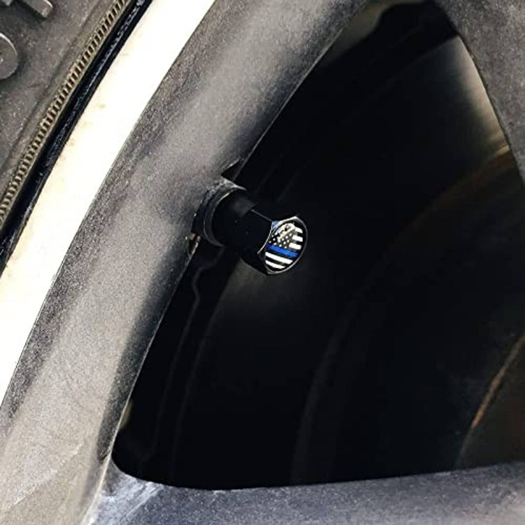 Black tire valve stem cap with thin blue line flag emblem installed on a wheel