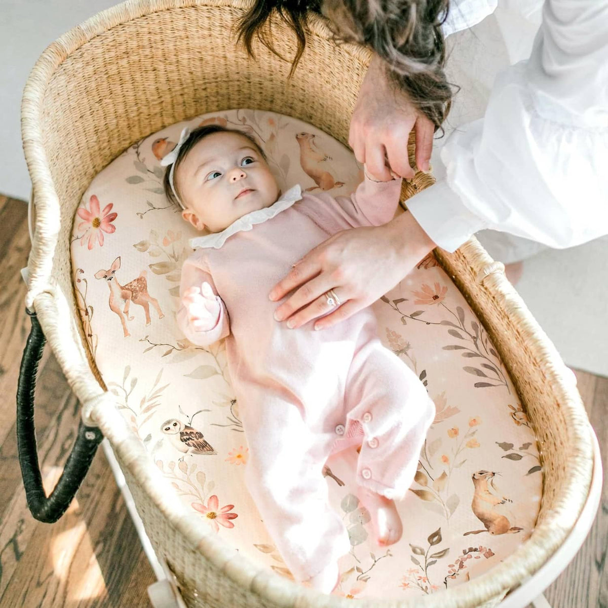 Blush floral woodland fitted bassinet sheet in woven bassinet with baby