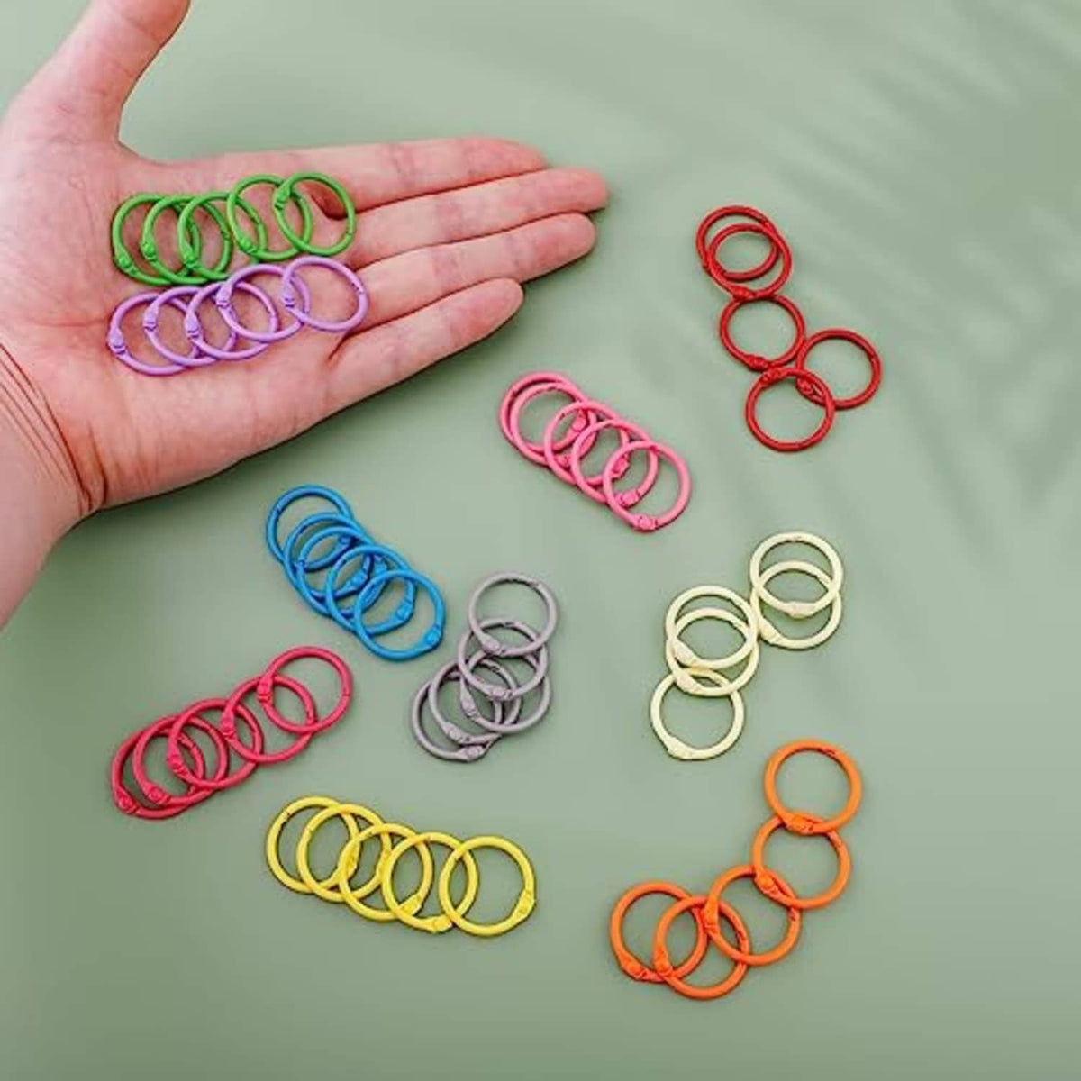 Assorted color binder rings held in a hand and grouped on a flat surface