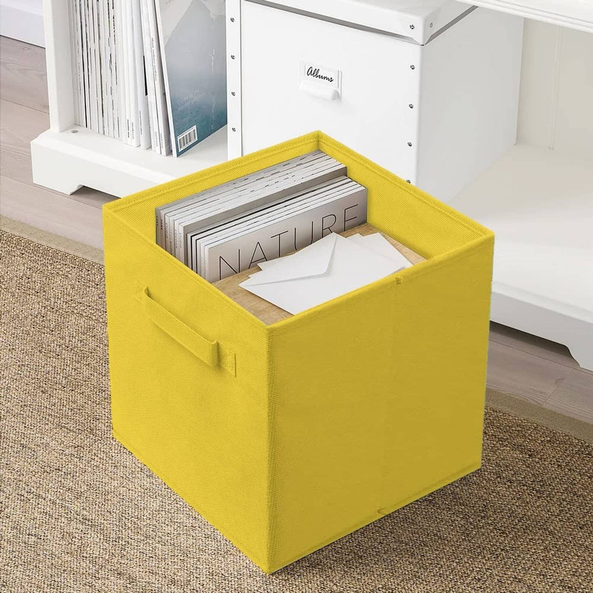 Yellow foldable fabric storage cube with a front handle and open top.
