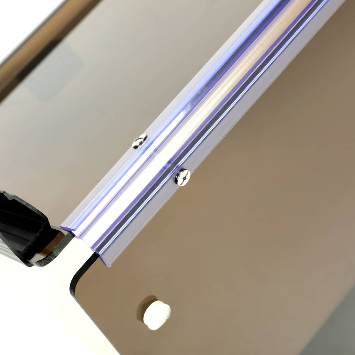 Close-up of tinted windshield with silver rails and black fastener hardware