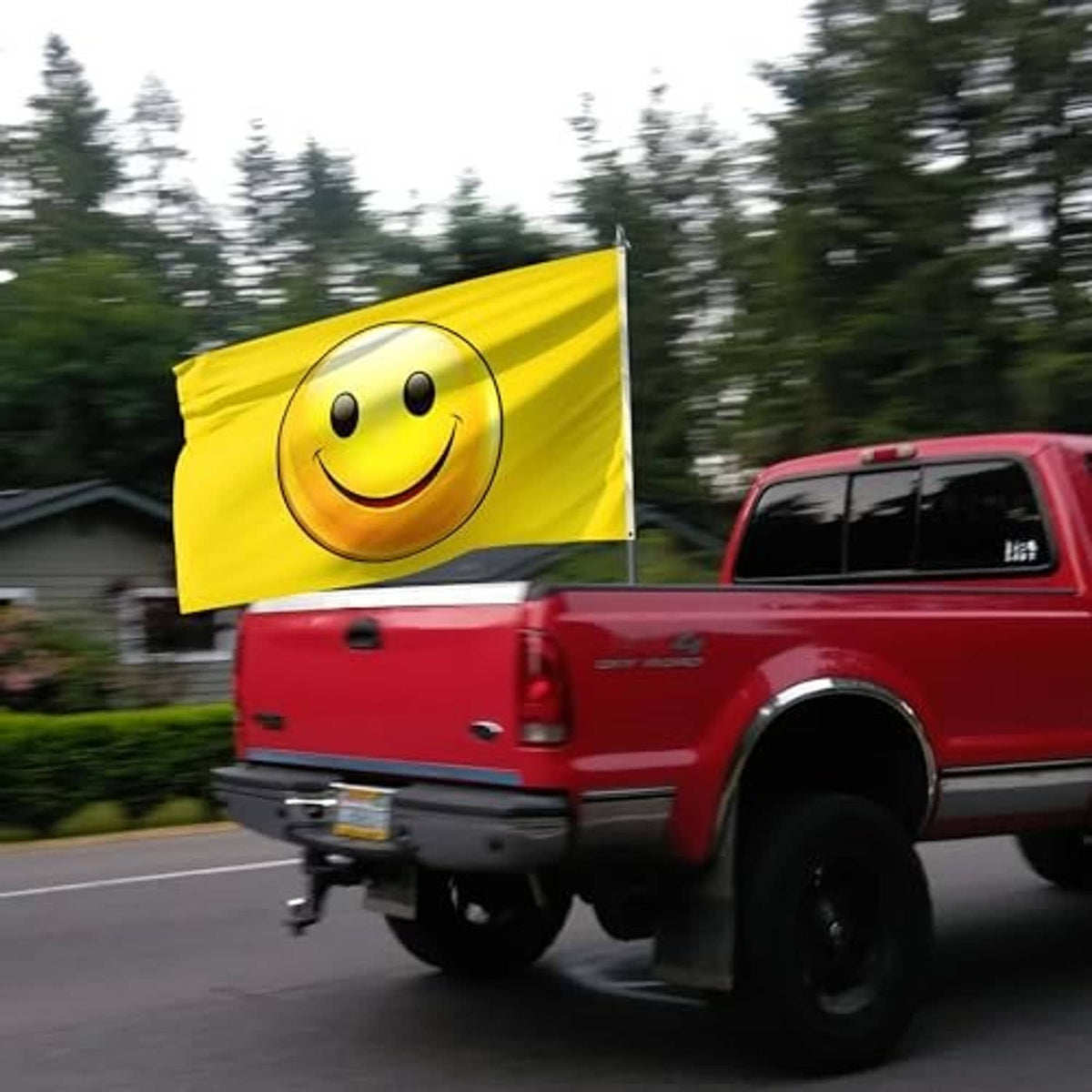 Yellow smiley face flag on a road near a red pickup truck