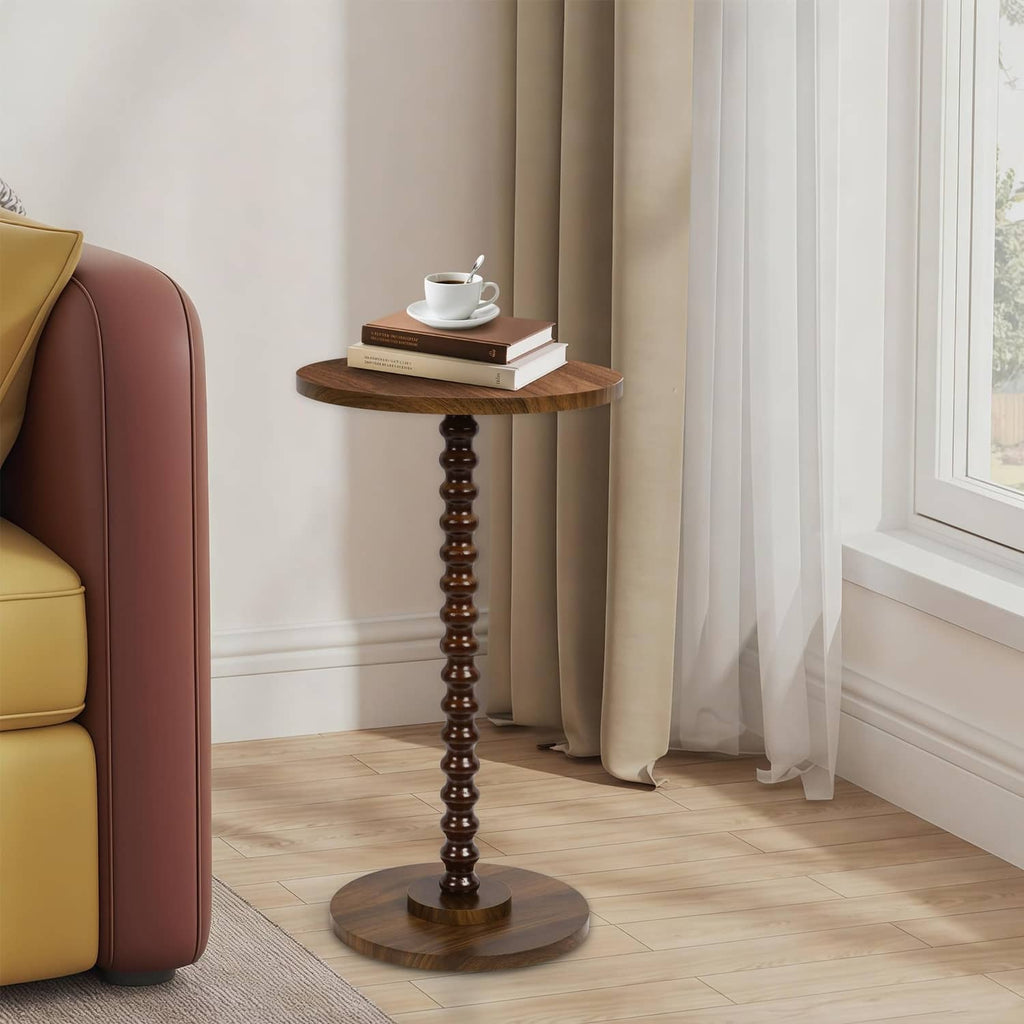 Rustic brown round side table with turned pedestal base, holding cup and book