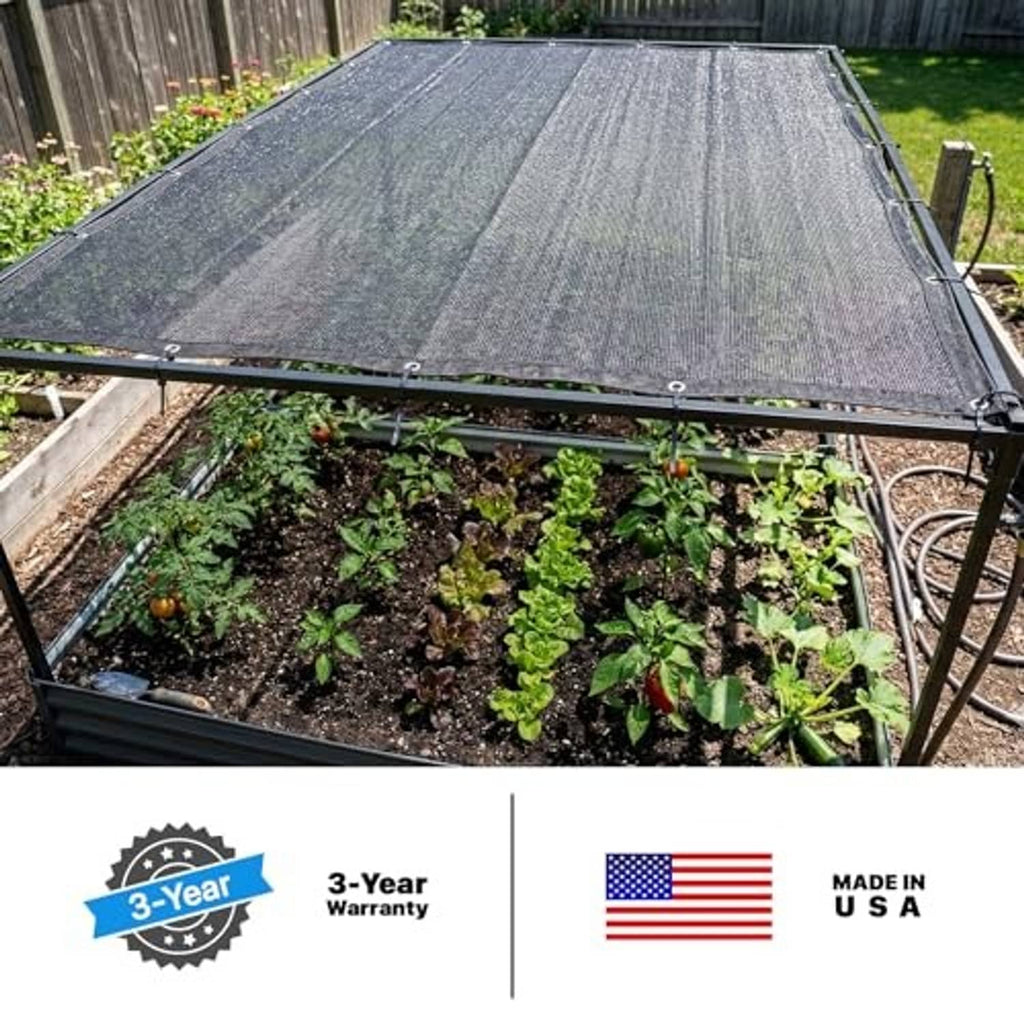 Black 50% shade cloth tarp over a garden bed frame with secured corners