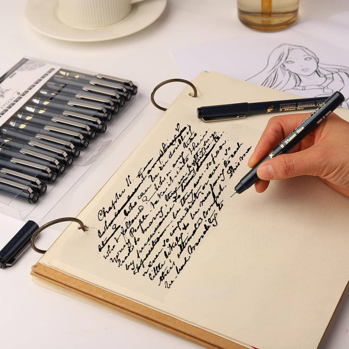 Hand writes with black needle drawing fineliner pen in a sketchbook
