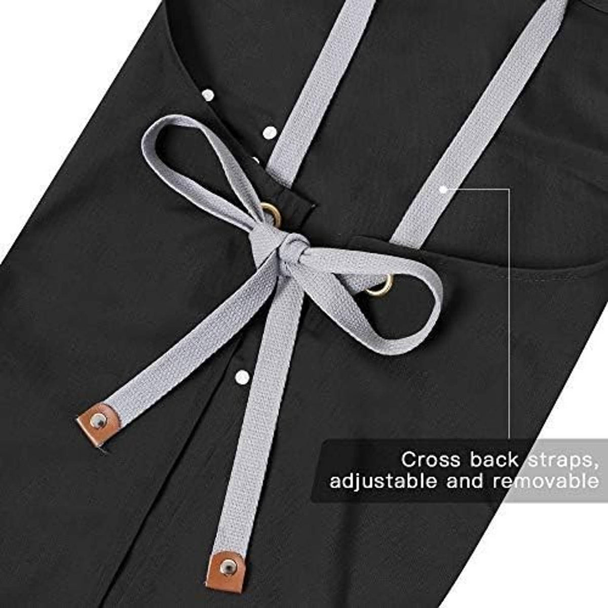 Black apron close-up with cross-back gray straps and brown leather strap fasteners