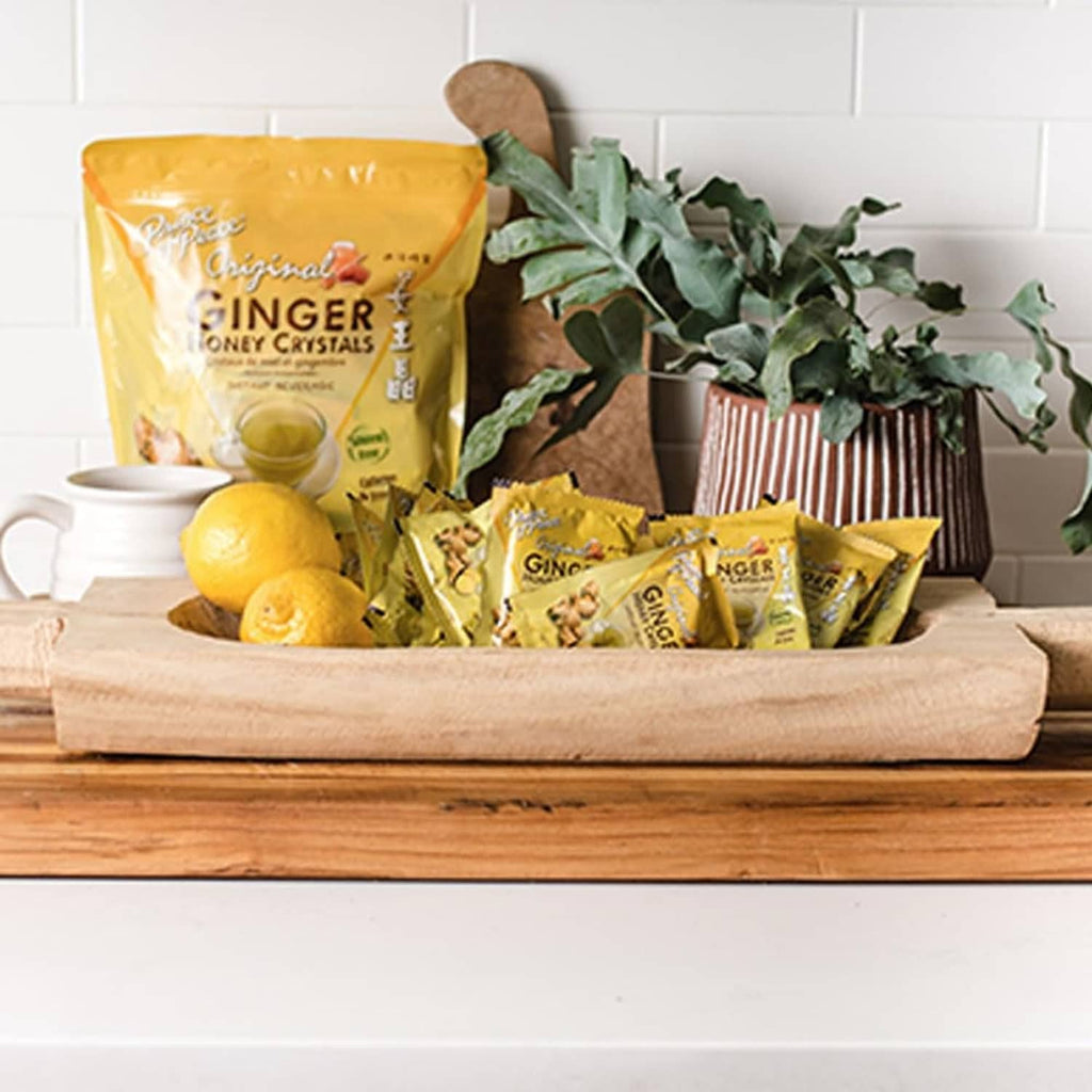 Ginger honey crystals pouch and small sachets on a wooden tray with lemons