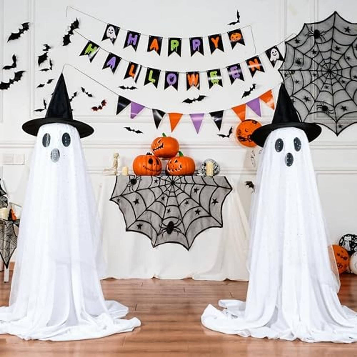 Two standing ghost decorations with black hats, dotted faces, and white draped sheer fabric for Halloween.