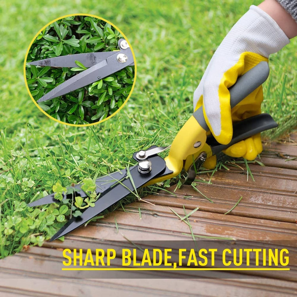 Yellow grass shears with dark blades held beside green plants for trimming