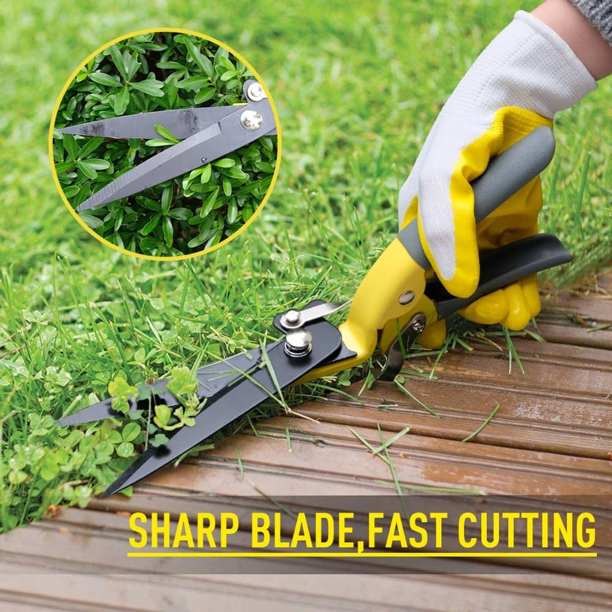 Yellow grass shears with dark blades held beside green plants for trimming