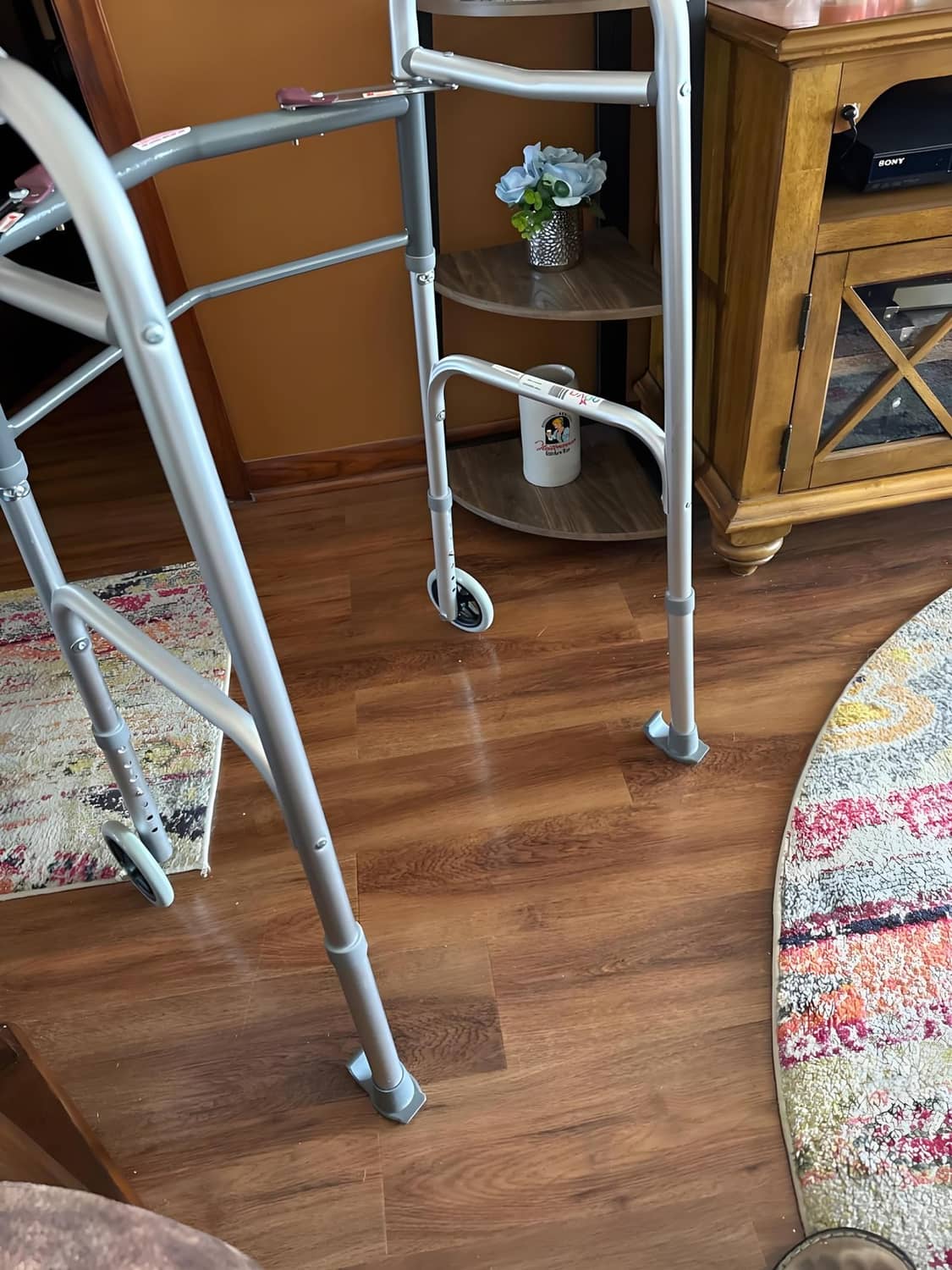 Grey ski glides mounted on folding walker legs, indoors on wood floor