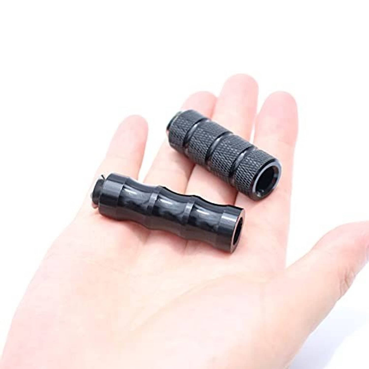 Black knurled motorcycle foot pegs with rubber sleeves, held in a hand