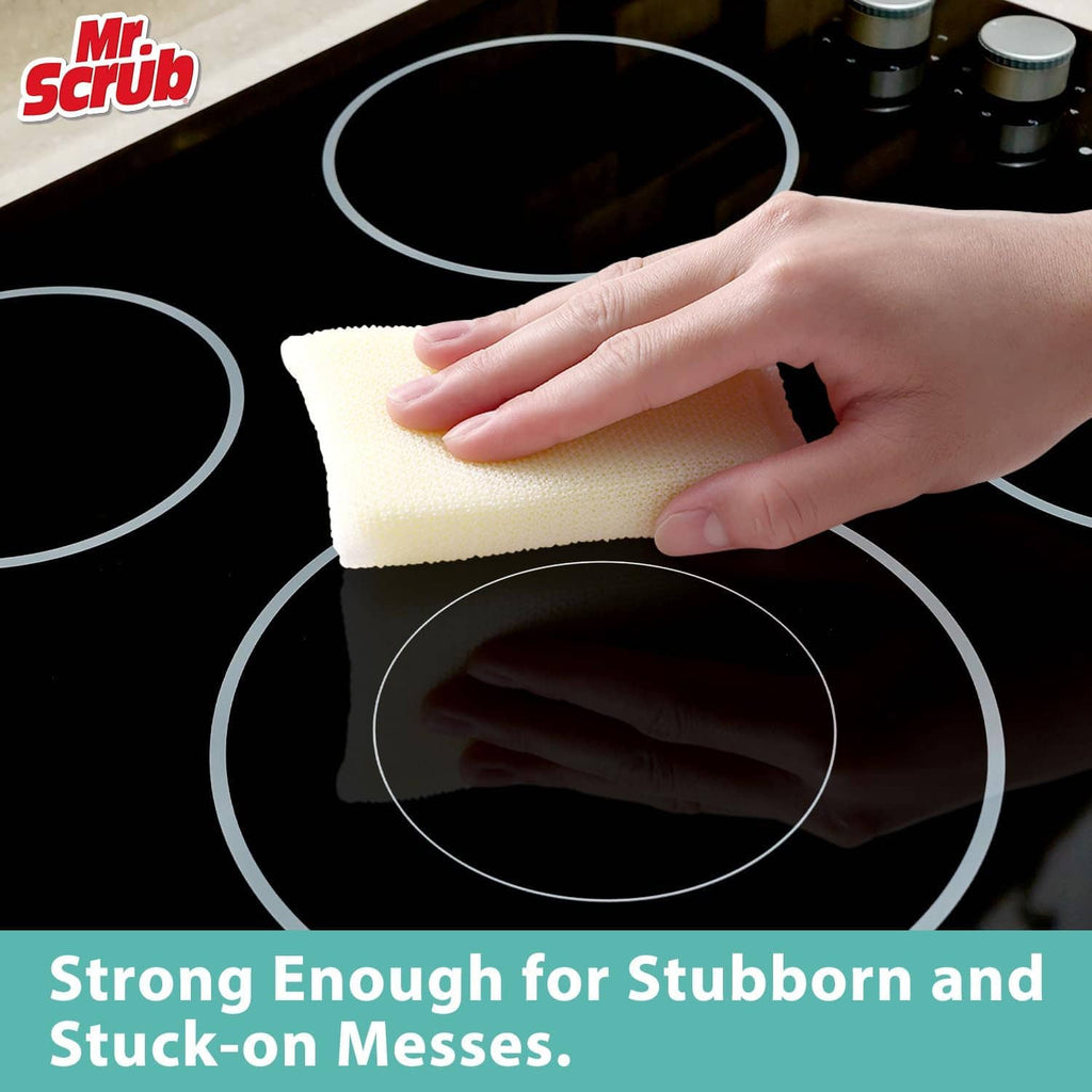 Hand holds a pale yellow non-scratch sponge on a stovetop