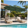Dark green patio umbrella with open canopy and metal pole beside outdoor lounge chairs