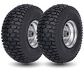 Pair of black lawn mower tires with silver wheel rims and deep tread pattern