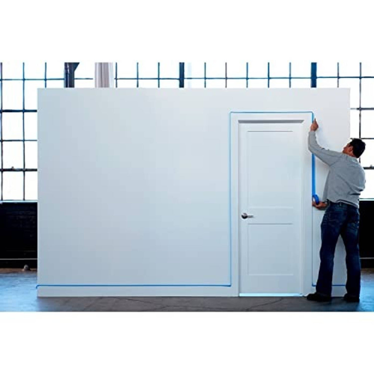 Blue painter's tape around a doorway and wall corner before painting
